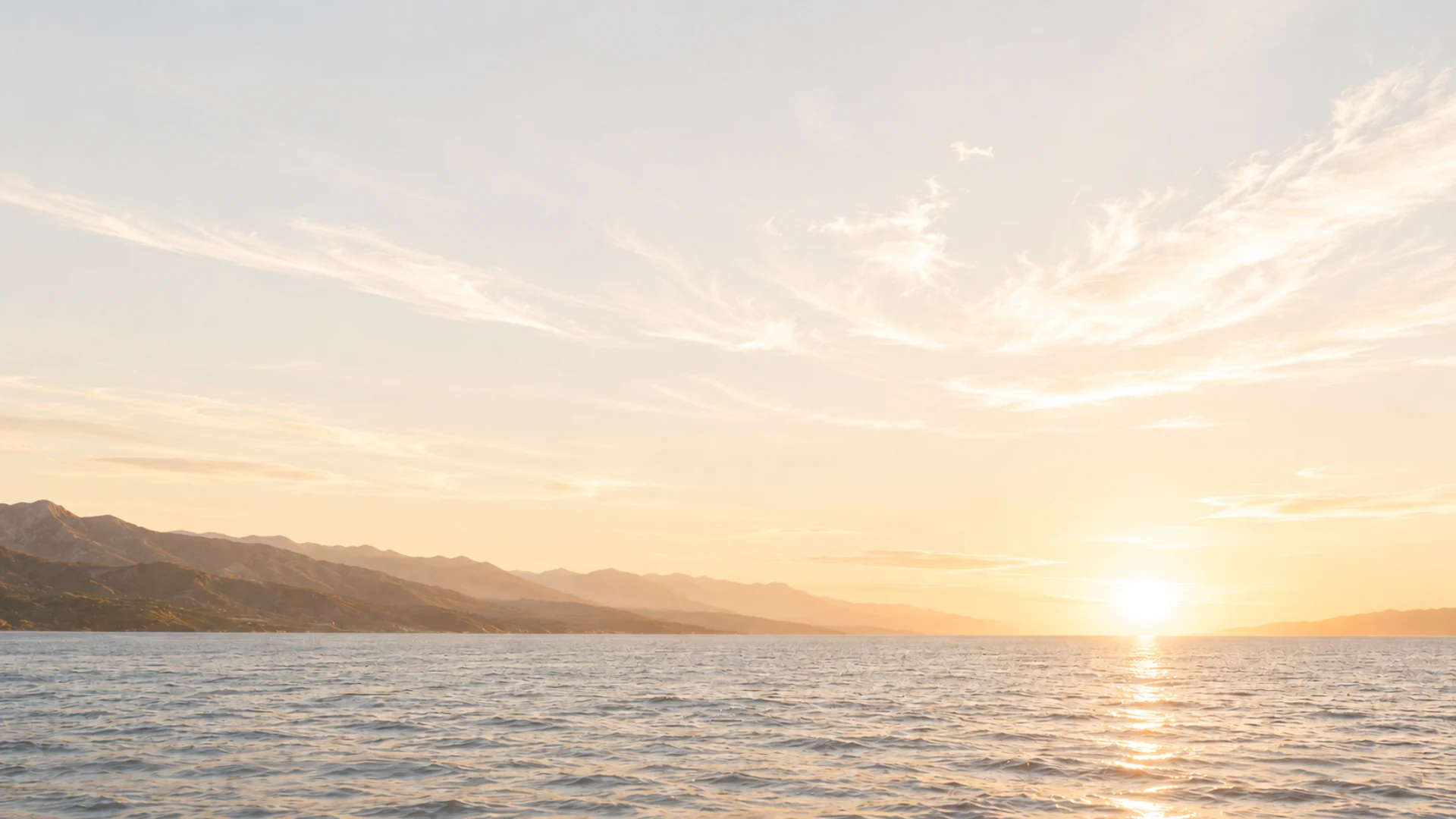 Amanecer sobre el mar con montañas en la costa