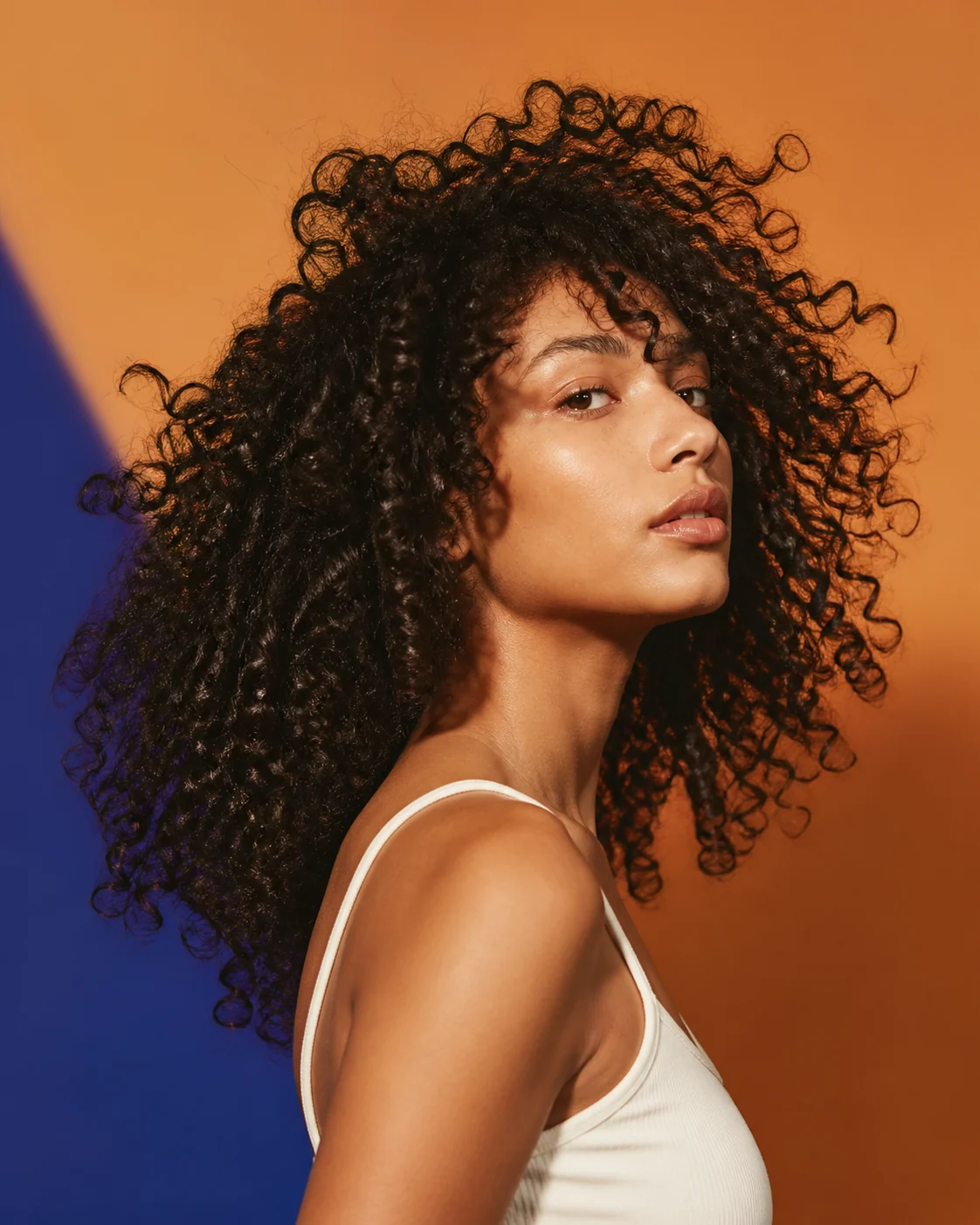 Cabello rizado con volumen sobre fondo naranja